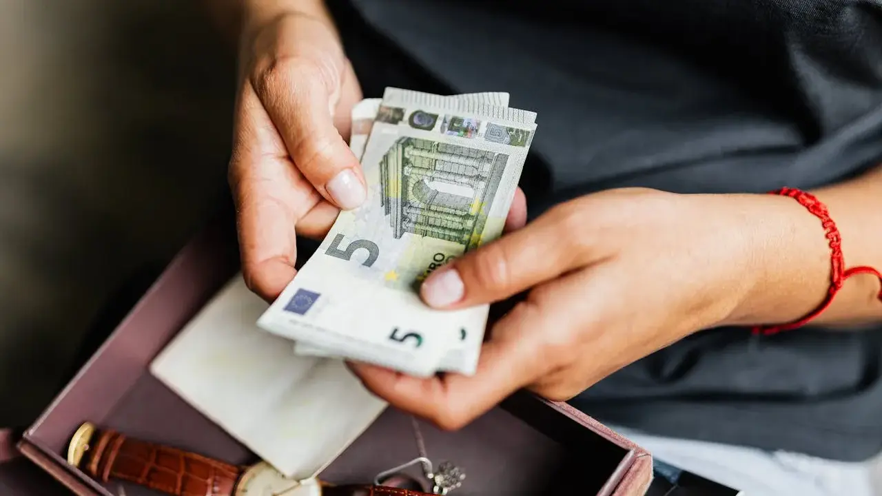 Dłonie liczą euro. Może to oszczędności na emeryturę zagraniczną po mężu, obok zegarka i pamiątek.