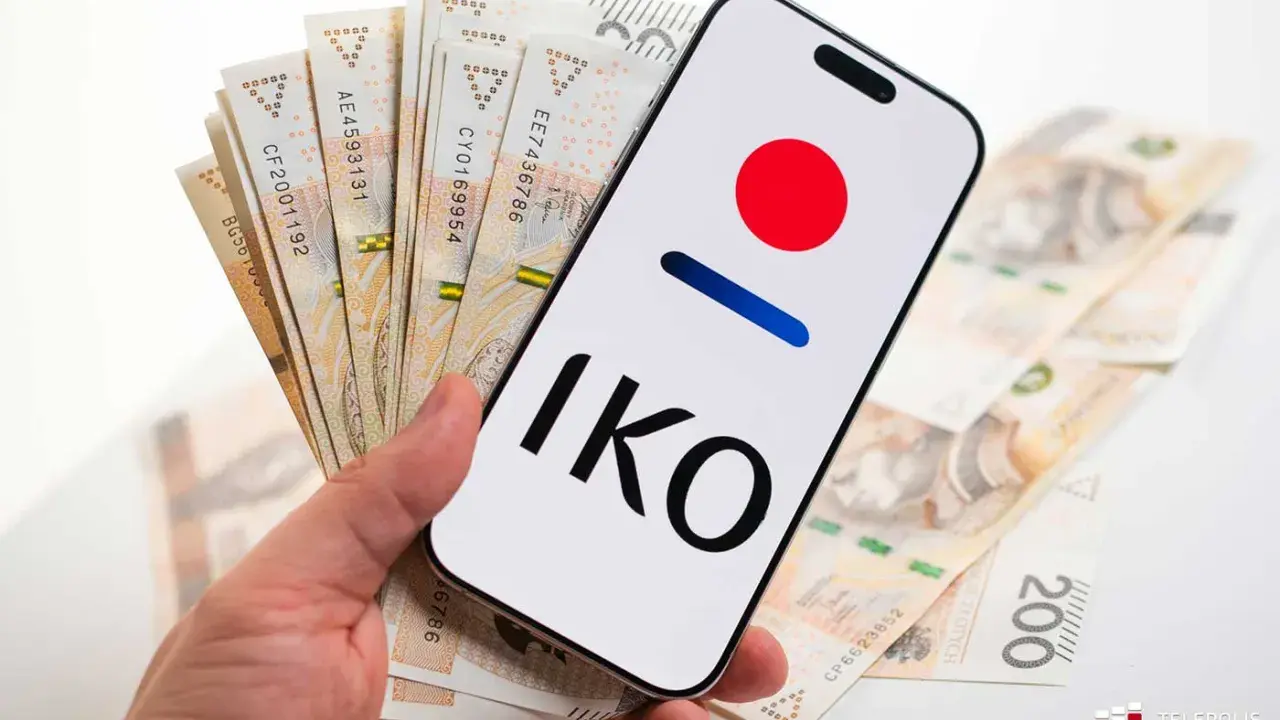 Dłoń trzyma smartfon z logo IKO PKO BP i polskie banknoty. Karta czasowo zablokowana pko? Nie, to tylko gotówka i aplikacja.