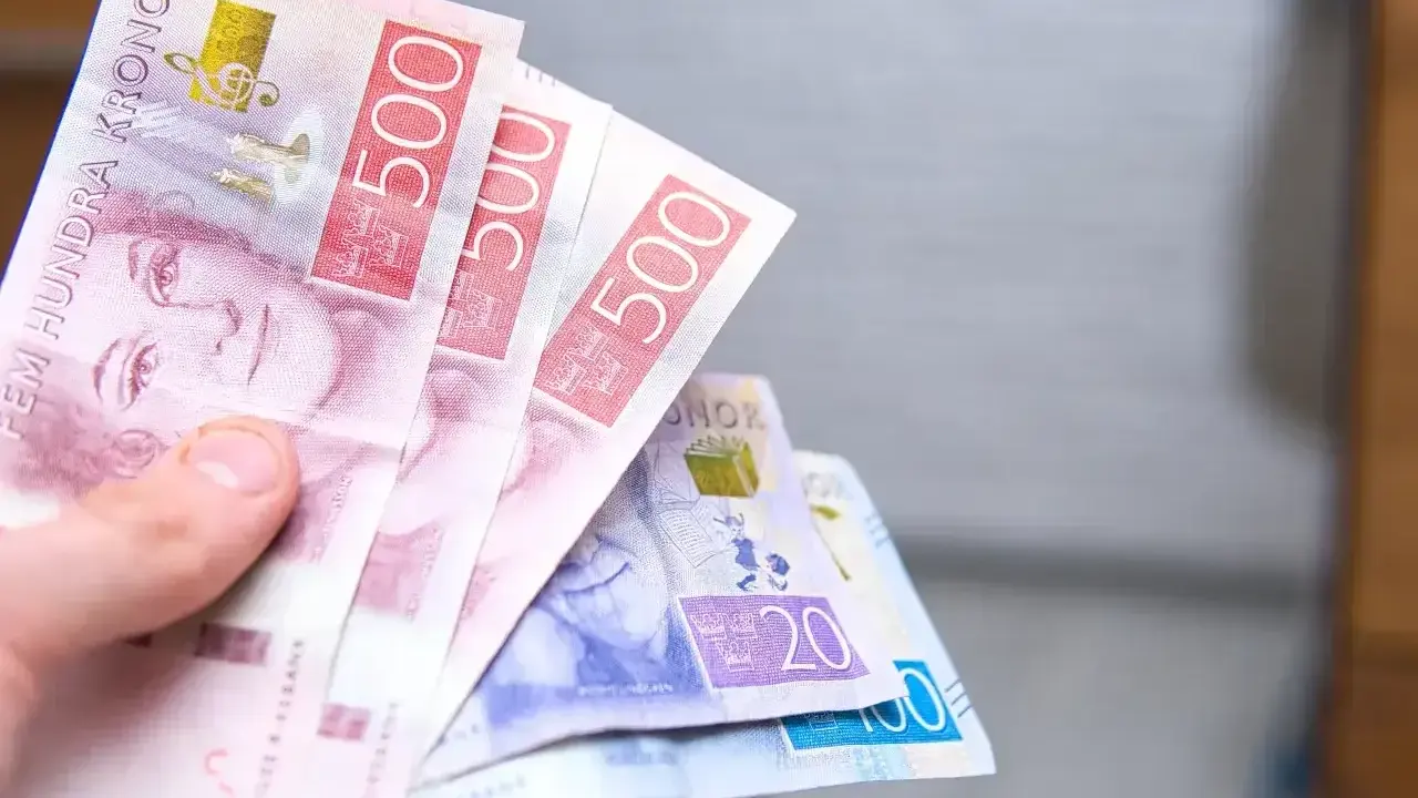 Dłoń trzyma banknoty 500 koron szwedzkich. Jaka waluta w Szwecji? Korona szwedzka.