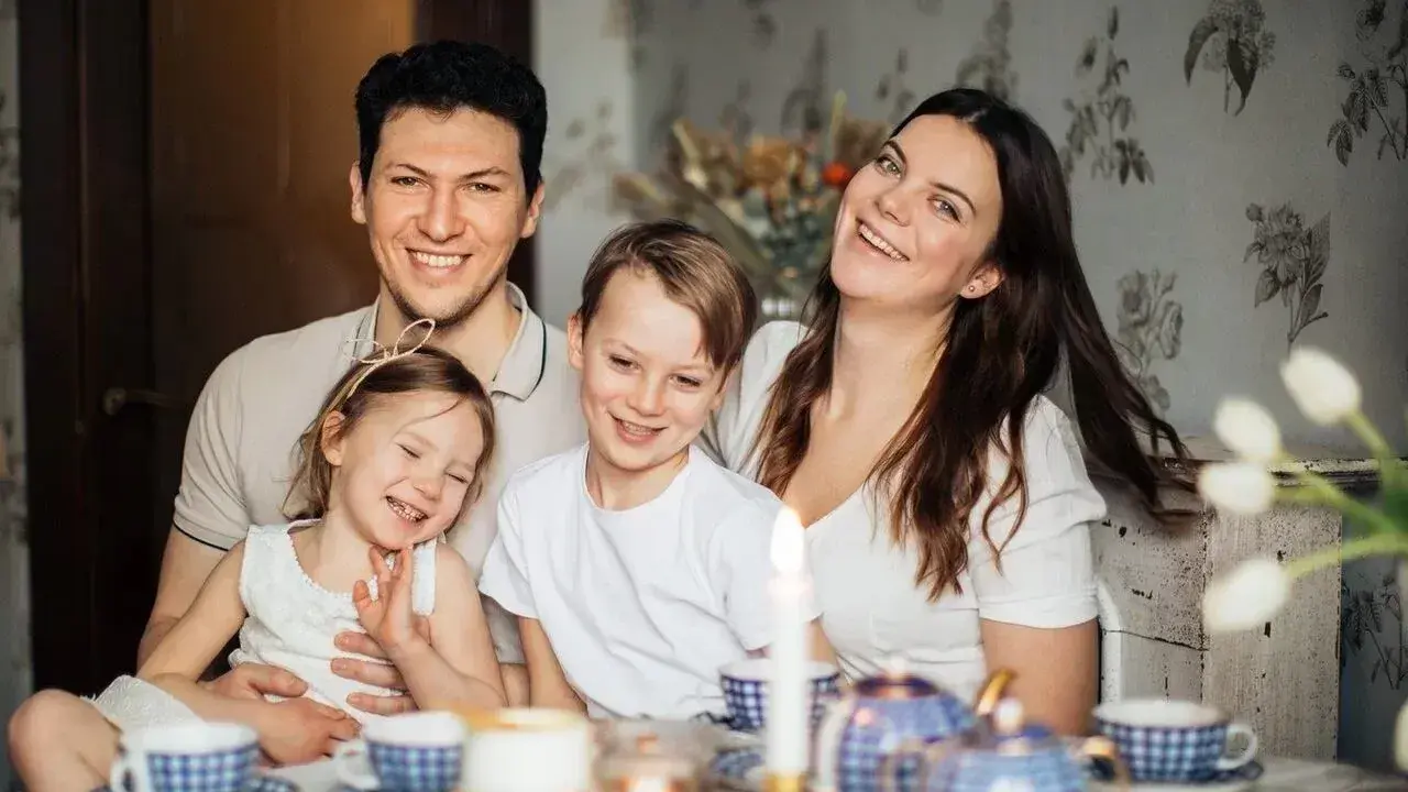 Szczęśliwa rodzina przy stole. Rodzice planują przyszłość, marząc o studiach zaocznych i wspierając dzieci, które pewnie skorzystają z kindergeld.