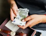 Dłonie liczą euro. Może to oszczędności na emeryturę zagraniczną po mężu, obok zegarka i pamiątek.