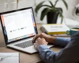 Osoba pracuje na laptopie, szukając informacji o zwrot podatku z Norwegii kiedy. Na biurku kawa i książki.