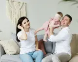 Szczęśliwa rodzinna sesja w Holandii. Tata podrzuca córeczkę, mama uśmiecha się obok.