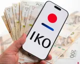 Dłoń trzyma smartfon z logo IKO PKO BP i polskie banknoty. Karta czasowo zablokowana pko? Nie, to tylko gotówka i aplikacja.