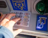 Dłoń wpisuje PIN na bankomacie. Co zrobić, gdy bankomat wciągnął kartę i jak załatwić zwrot?