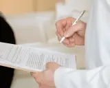 Ręka trzymająca długopis nad dokumentami. Widać fragmenty formularzy, które mogą być związane z Familienkasse druki po polsku.