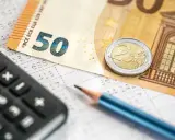 Kalkulator, ołówek i banknot 50 euro na arkuszu z danymi. Obliczanie podatku dochodowego i potencjalnego zwrotu.