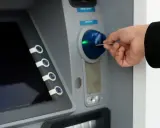 Dłoń wkłada kartę do bankomatu, próbując uzyskać dostęp do środków, ale konto bankowe jest zablokowane.