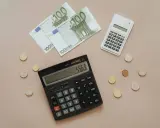 Euro banknoty i monety, dwa kalkulatory. Obliczanie, co można odliczyć od podatku w Niemczech, staje się prostsze.