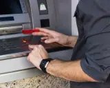 Mężczyzna wkłada kartę do bankomatu, przygotowując się, jak wypłacić pieniądze z bankomatu za granicą.
