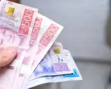 Dłoń trzyma banknoty 500 koron szwedzkich. Jaka waluta w Szwecji? Korona szwedzka.