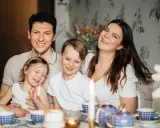 Szczęśliwa rodzina przy stole. Rodzice planują przyszłość, marząc o studiach zaocznych i wspierając dzieci, które pewnie skorzystają z kindergeld.