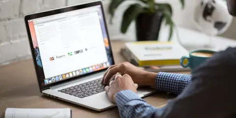 Osoba pracuje na laptopie, szukając informacji o zwrot podatku z Norwegii kiedy. Na biurku kawa i książki.