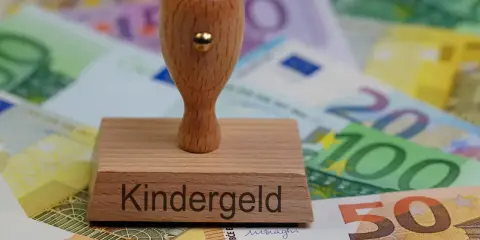 Stempel z napisem "Kindergeld" na tle banknotów euro. Symbol wsparcia dla rodzin, które mogą ubiegać się o świadczenia na dzieci mieszkające w Polsce.