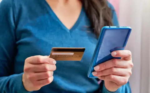Kobieta trzyma kartę i telefon, planując jak przelać pieniadze z Revoluta.
