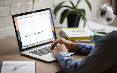Osoba pracuje na laptopie, szukając informacji o zwrot podatku z Norwegii kiedy. Na biurku kawa i książki.
