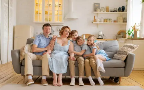 Szczęśliwa rodzina na kanapie. Rodzice i trójka dzieci, marzą o wsparciu finansowym, jak kinderzuschlag, by zapewnić im lepszą przyszłość.