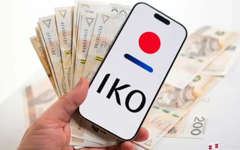 Dłoń trzyma smartfon z logo IKO PKO BP i polskie banknoty. Karta czasowo zablokowana pko? Nie, to tylko gotówka i aplikacja.