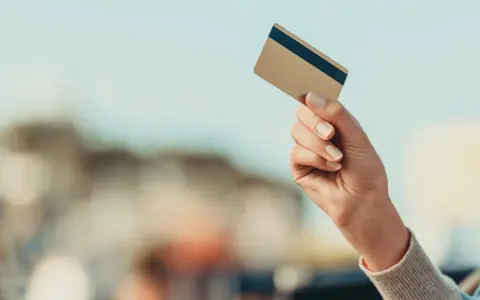 Dłoń trzyma kartę płatniczą, gotowa do transakcji. Dowiedz się, jak płacić kartą za granicą bez obaw.