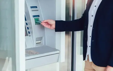 Mężczyzna wkłada kartę do wpłatomatu, który przyjmuje różne banknoty.