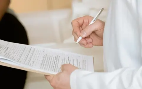Ręka trzymająca długopis nad dokumentami. Widać fragmenty formularzy, które mogą być związane z Familienkasse druki po polsku.