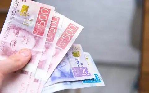 Dłoń trzyma banknoty 500 koron szwedzkich. Jaka waluta w Szwecji? Korona szwedzka.