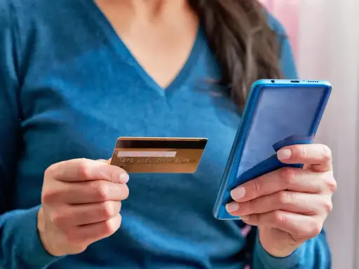Kobieta trzyma kartę i telefon, planując jak przelać pieniadze z Revoluta.