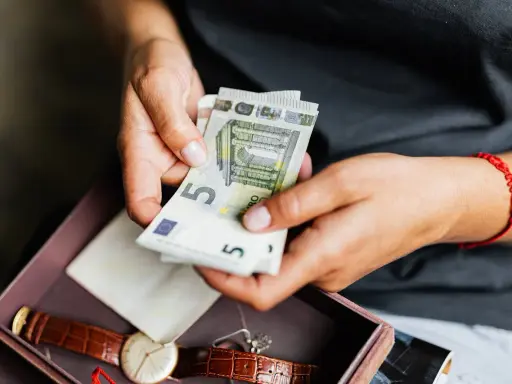 Dłonie liczą euro. Może to oszczędności na emeryturę zagraniczną po mężu, obok zegarka i pamiątek.