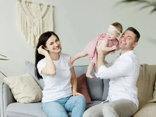 Szczęśliwa rodzinna sesja w Holandii. Tata podrzuca córeczkę, mama uśmiecha się obok.