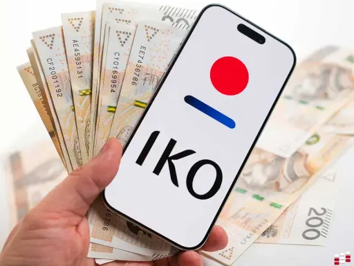 Dłoń trzyma smartfon z logo IKO PKO BP i polskie banknoty. Karta czasowo zablokowana pko? Nie, to tylko gotówka i aplikacja.