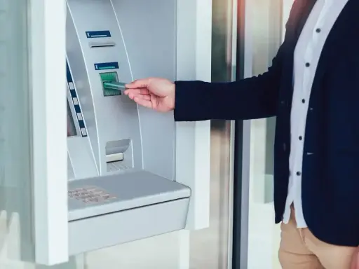 Mężczyzna wkłada kartę do wpłatomatu, który przyjmuje różne banknoty.
