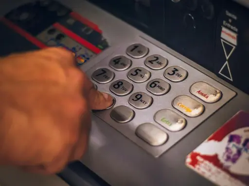 Dłoń naciska klawisz bankomatu, przygotowując się do transakcji. Szybko i sprawnie jak wypłacić czek blik z bankomatu.