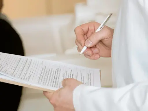 Ręka trzymająca długopis nad dokumentami. Widać fragmenty formularzy, które mogą być związane z Familienkasse druki po polsku.