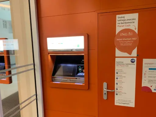 Bankomat Planet Cash z informacją o braku prowizji dla klientów ING. W pobliżu znajduje się też plakat o koronawirusie.