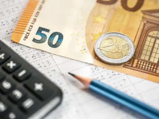 Kalkulator, ołówek i banknot 50 euro na arkuszu z danymi. Obliczanie podatku dochodowego i potencjalnego zwrotu.