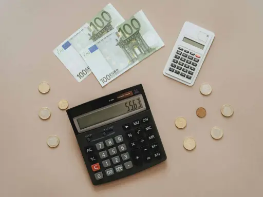 Euro banknoty i monety, dwa kalkulatory. Obliczanie, co można odliczyć od podatku w Niemczech, staje się prostsze.