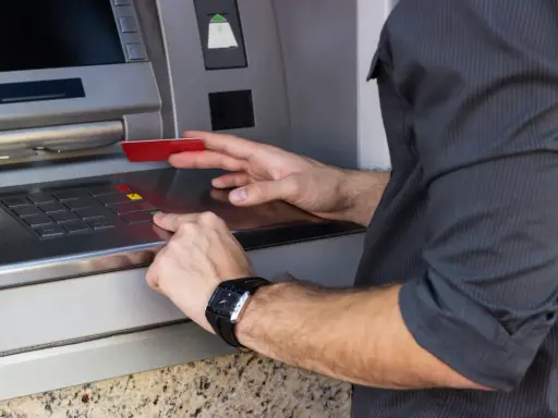 Mężczyzna wkłada kartę do bankomatu, przygotowując się, jak wypłacić pieniądze z bankomatu za granicą.