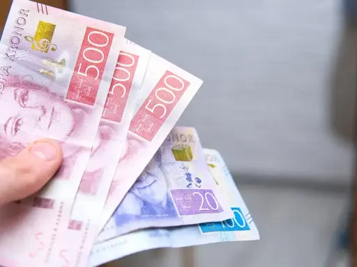 Dłoń trzyma banknoty 500 koron szwedzkich. Jaka waluta w Szwecji? Korona szwedzka.