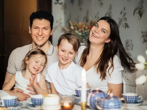 Szczęśliwa rodzina przy stole. Rodzice planują przyszłość, marząc o studiach zaocznych i wspierając dzieci, które pewnie skorzystają z kindergeld.