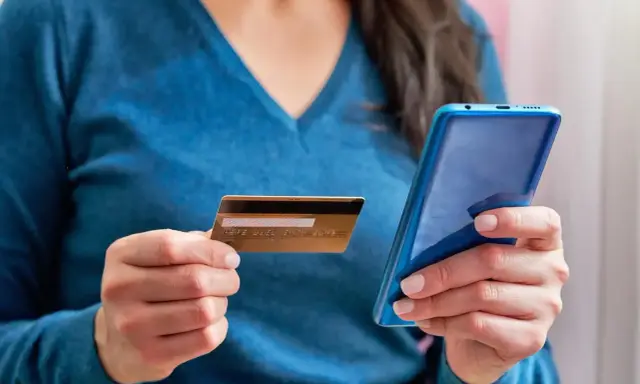 Kobieta trzyma kartę i telefon, planując jak przelać pieniadze z Revoluta.