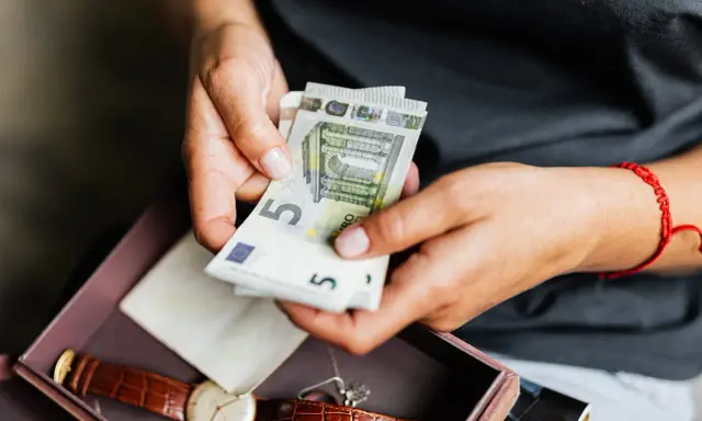 Dłonie liczą euro. Może to oszczędności na emeryturę zagraniczną po mężu, obok zegarka i pamiątek.