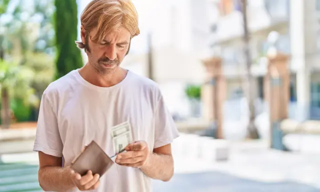 Mężczyzna z wąsami i blond włosami przegląda pieniądze w portfelu. Zastanawia się, co to jest loonheffing, gdy widzi banknoty.