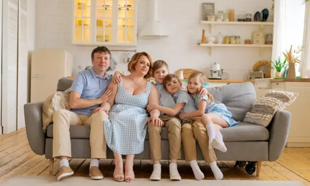 Szczęśliwa rodzina na kanapie. Rodzice i trójka dzieci, marzą o wsparciu finansowym, jak kinderzuschlag, by zapewnić im lepszą przyszłość.