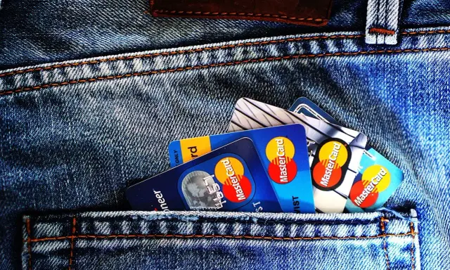 Kilka kart płatniczych, w tym Mastercard, w tylnej kieszeni dżinsów. Czy to preautoryzacja co to?