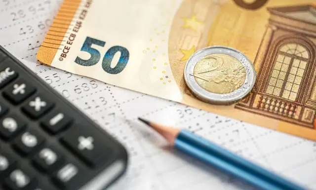 Kalkulator, ołówek i banknot 50 euro na arkuszu z danymi. Obliczanie podatku dochodowego i potencjalnego zwrotu.