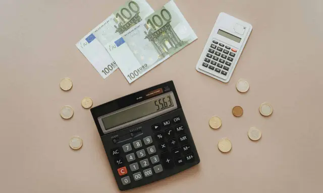 Euro banknoty i monety, dwa kalkulatory. Obliczanie, co można odliczyć od podatku w Niemczech, staje się prostsze.