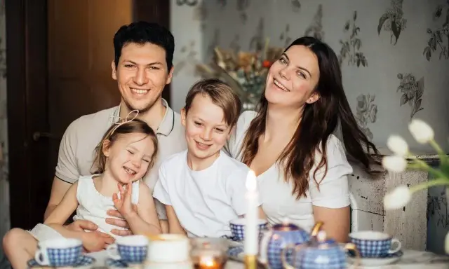 Szczęśliwa rodzina przy stole. Rodzice planują przyszłość, marząc o studiach zaocznych i wspierając dzieci, które pewnie skorzystają z kindergeld.