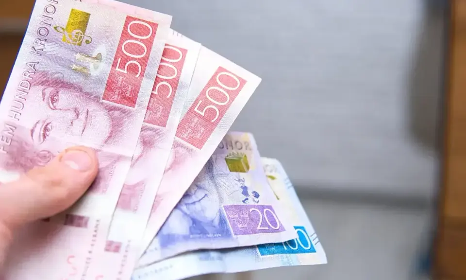 Dłoń trzyma banknoty 500 koron szwedzkich. Jaka waluta w Szwecji? Korona szwedzka.