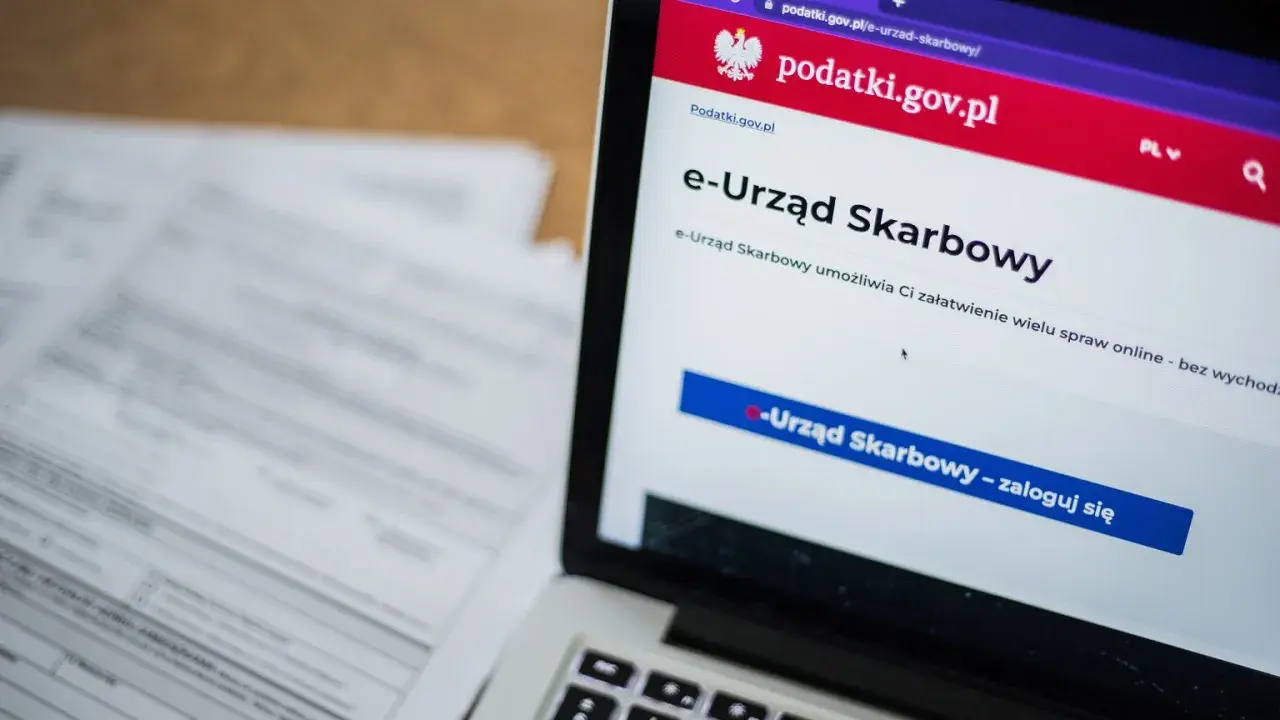 Laptop z otwartą stroną e-Urzędu Skarbowego. Obok leżą dokumenty, które mogą zawierać identyfikator zobowiązania.