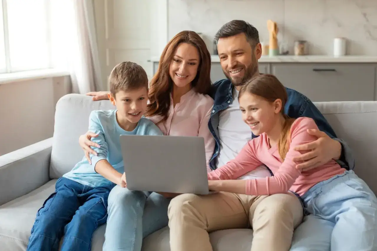 Rodzina ogląda coś na laptopie. Może szukają informacji o kinderzuschlag na dzieci mieszkające w Polsce, by zapewnić im lepszą przyszłość.